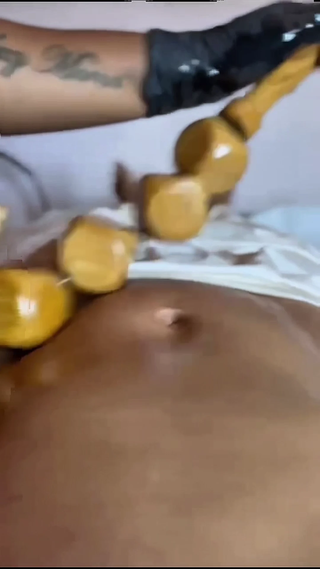 Geste de madérothérapie : outil en bois sculpté travaillant la zone abdominale
